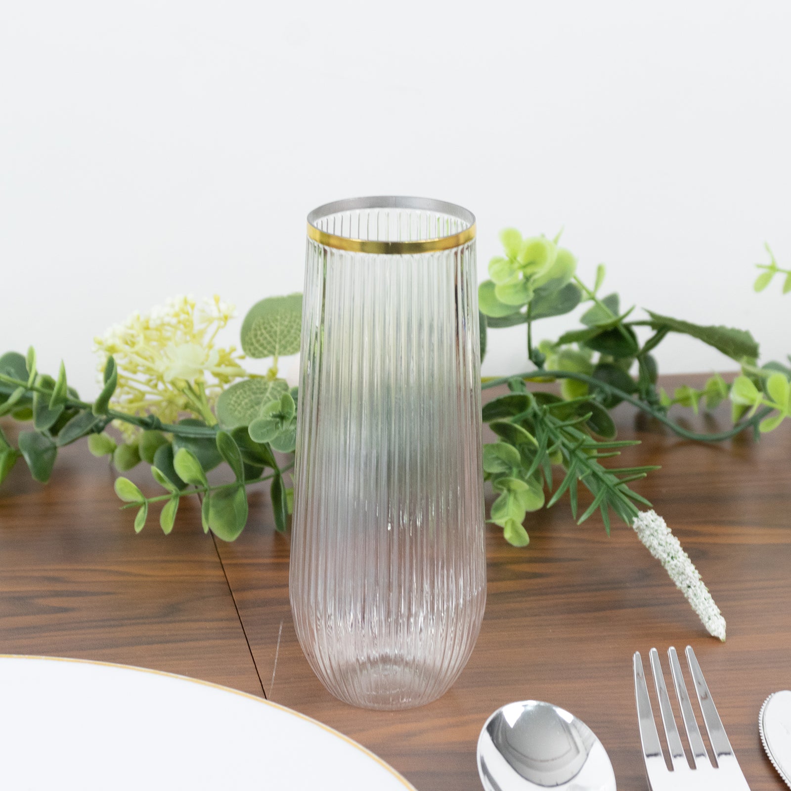 Clear with gold rim ribbed plastic champagne flute on a table setting.