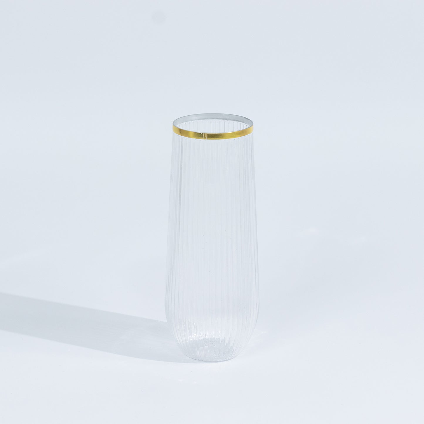 Clear stemless plastic champagne flute with gold rim.