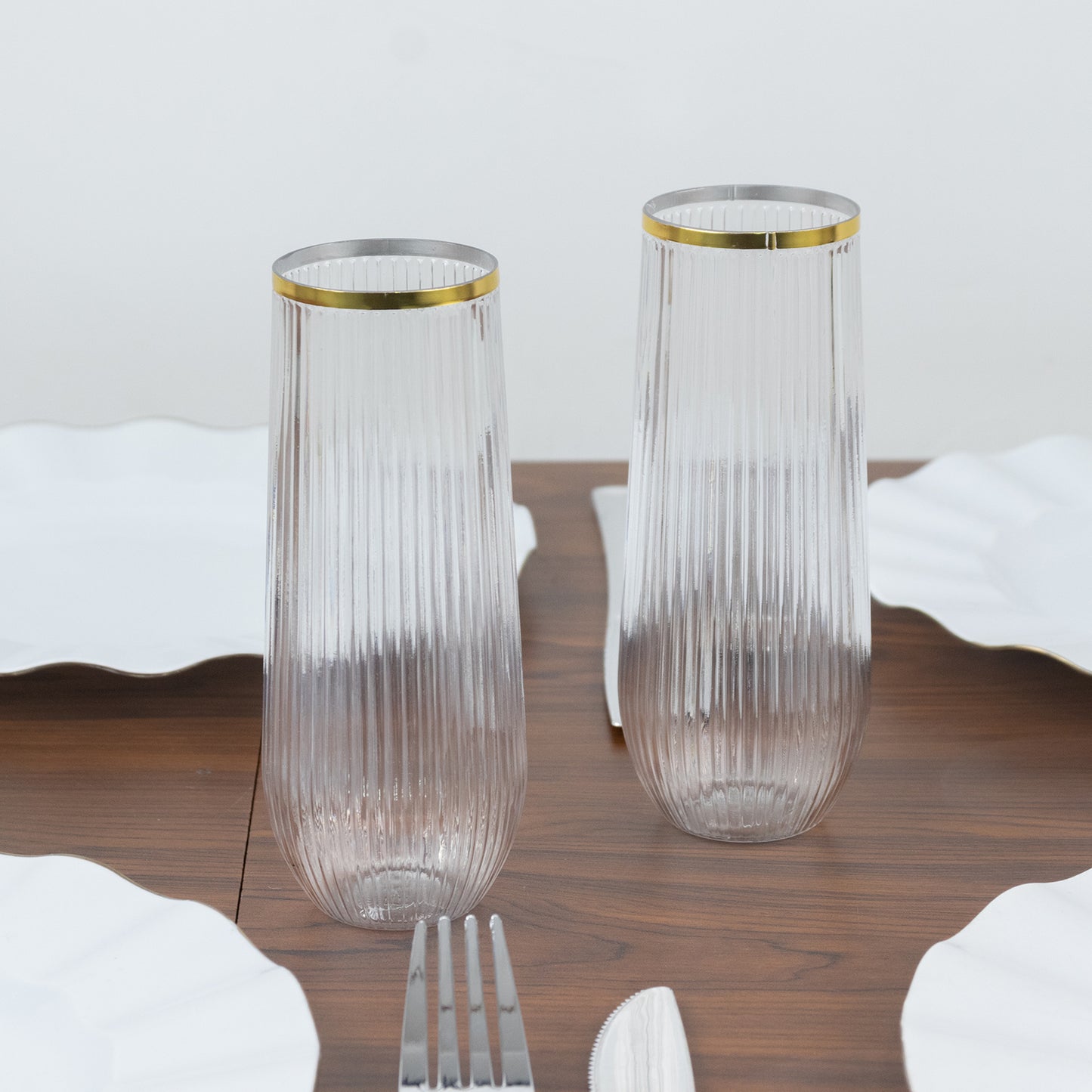 Clear ribbed plastic champagne flutes with gold rim.