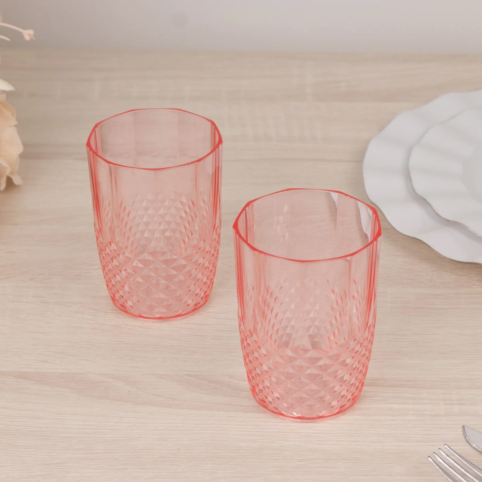Transparent blush reusable plastic tumbler glasses in crystal cut style.