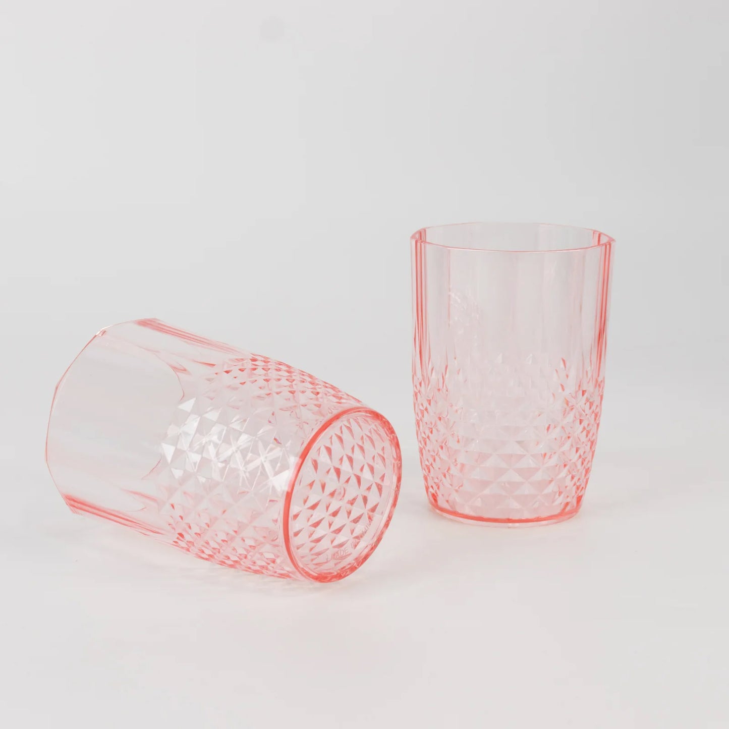 Transparent blush reusable plastic tumbler glasses in crystal cut style.