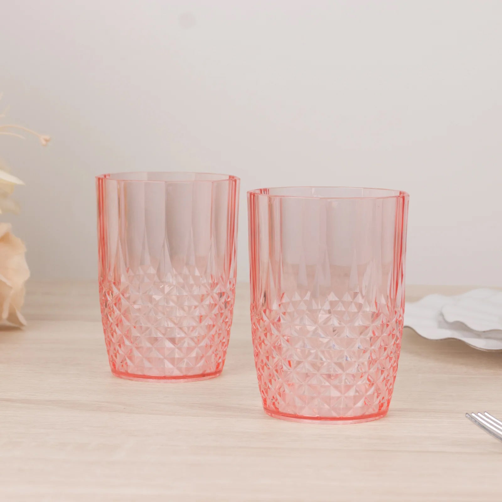 Transparent blush reusable plastic tumbler glasses in crystal cut style.