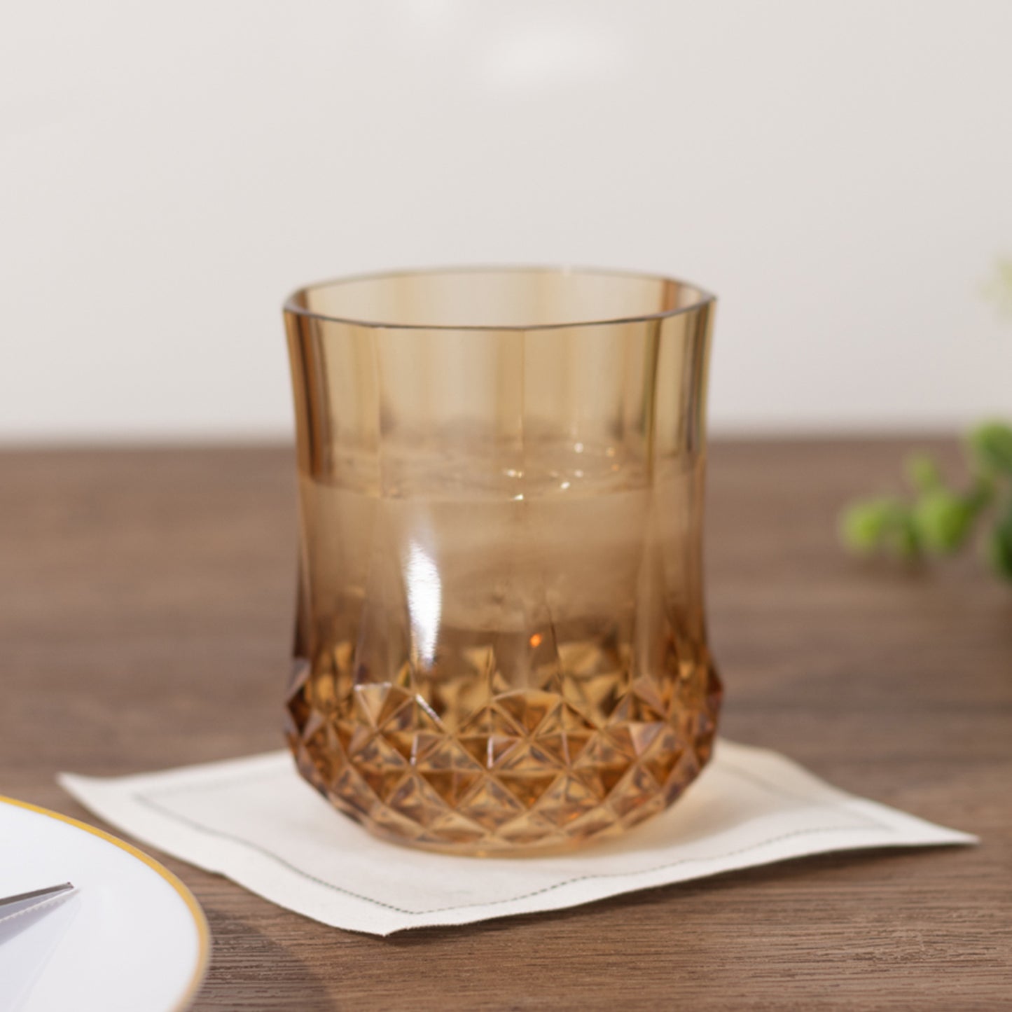 Amber gold crystal cut stemless wine glass on a table.