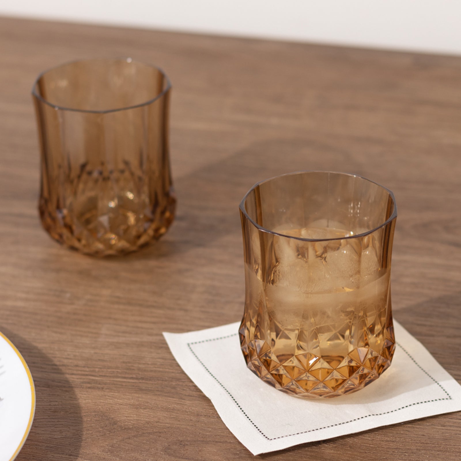Amber gold shatterproof stemless wine glasses on a wooden table.