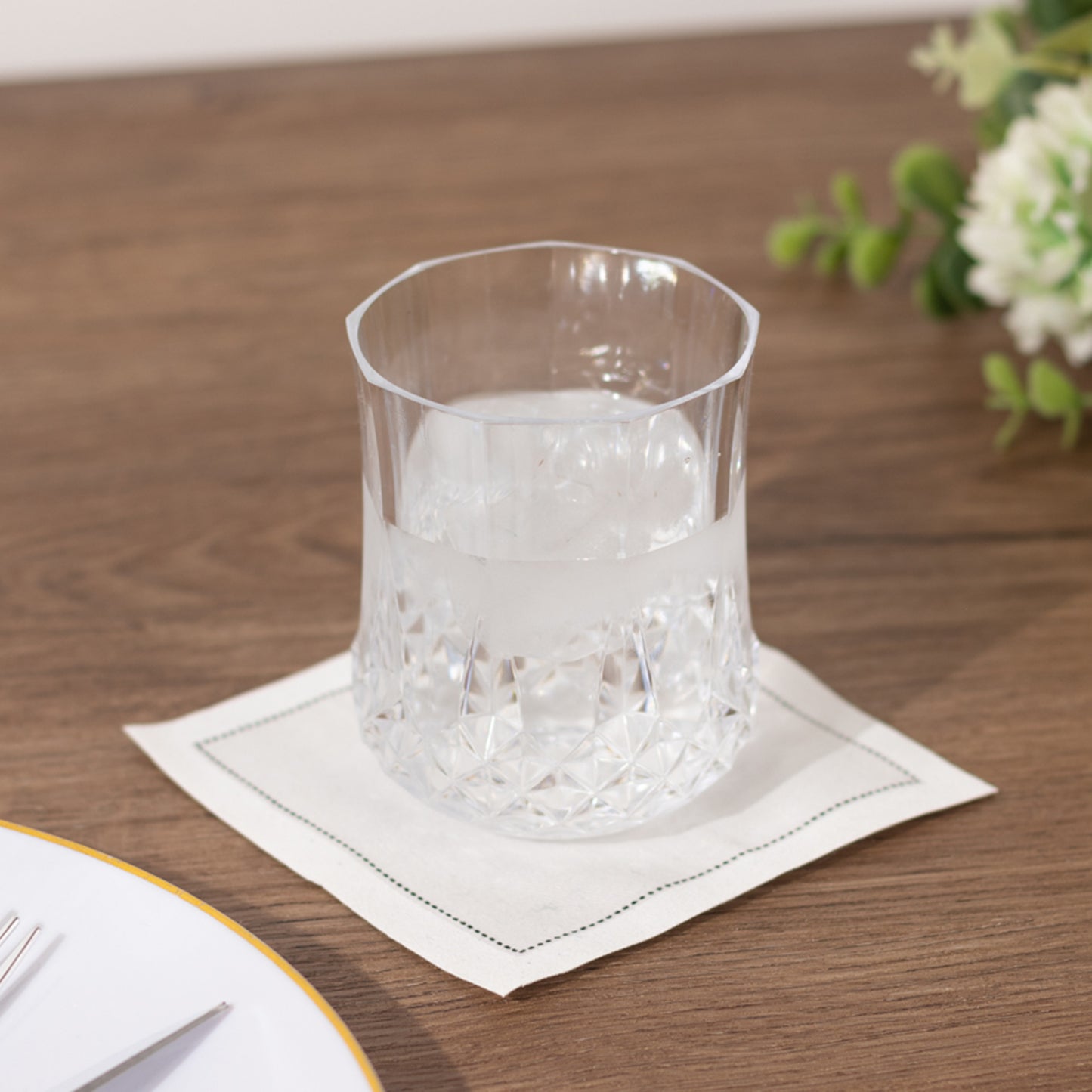 Clear crystal cut plastic stemless wine glass on a wooden table.