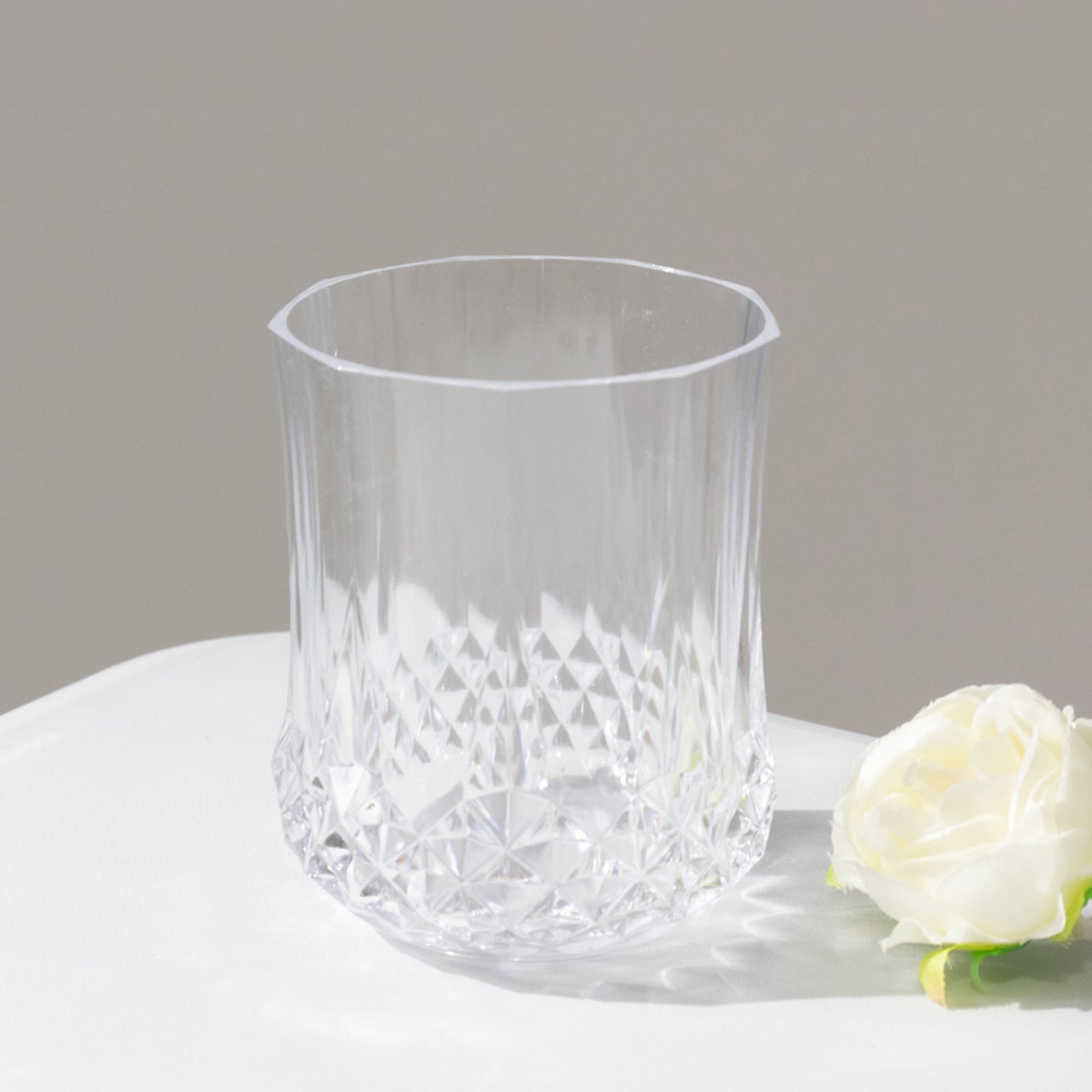 Clear crystal cut plastic stemless wine glass on a neutral background.