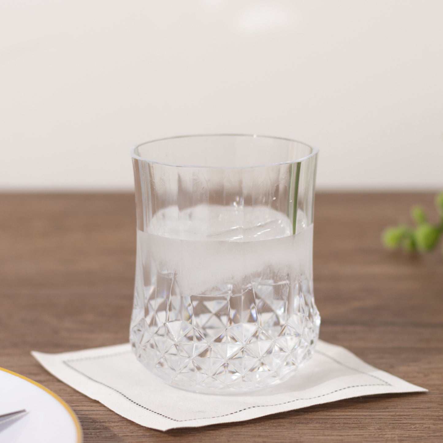 Clear crystal cut plastic stemless wine glass on a wooden table.