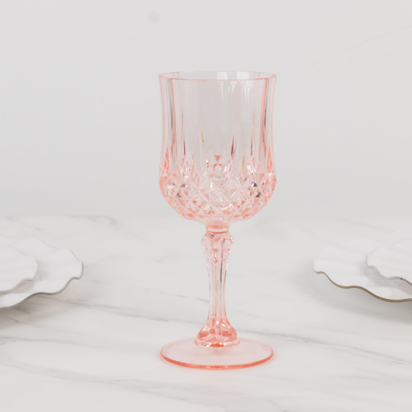 Transparent blush crystal cut reusable plastic cocktail goblet.