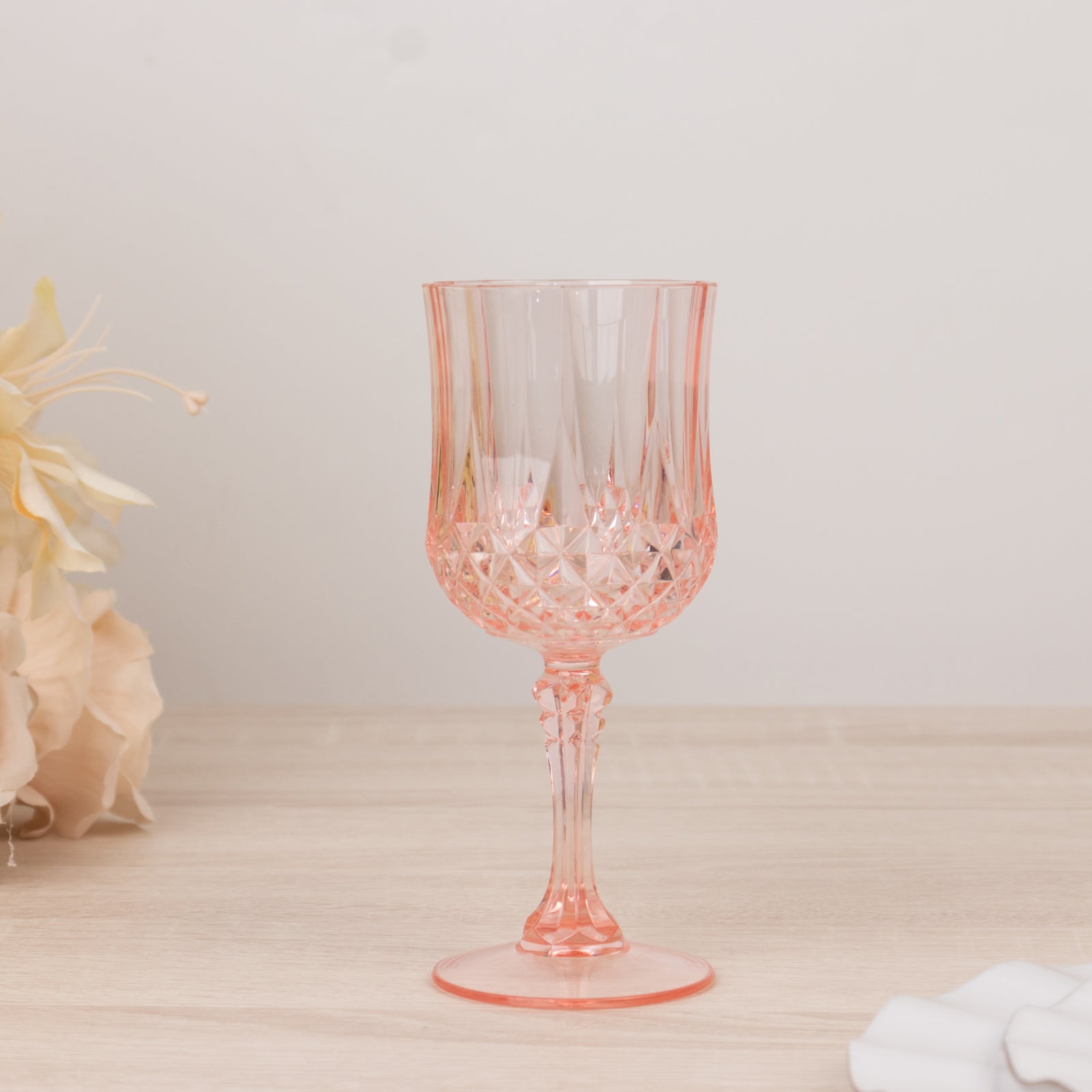 Transparent blush crystal cut reusable plastic cocktail goblet.