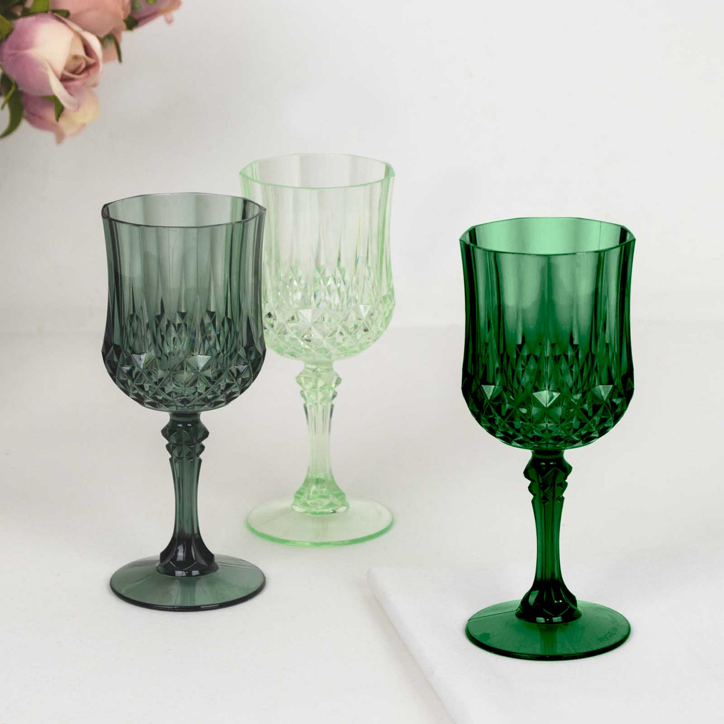 Assorted green crystal cut reusable plastic cocktail goblets.