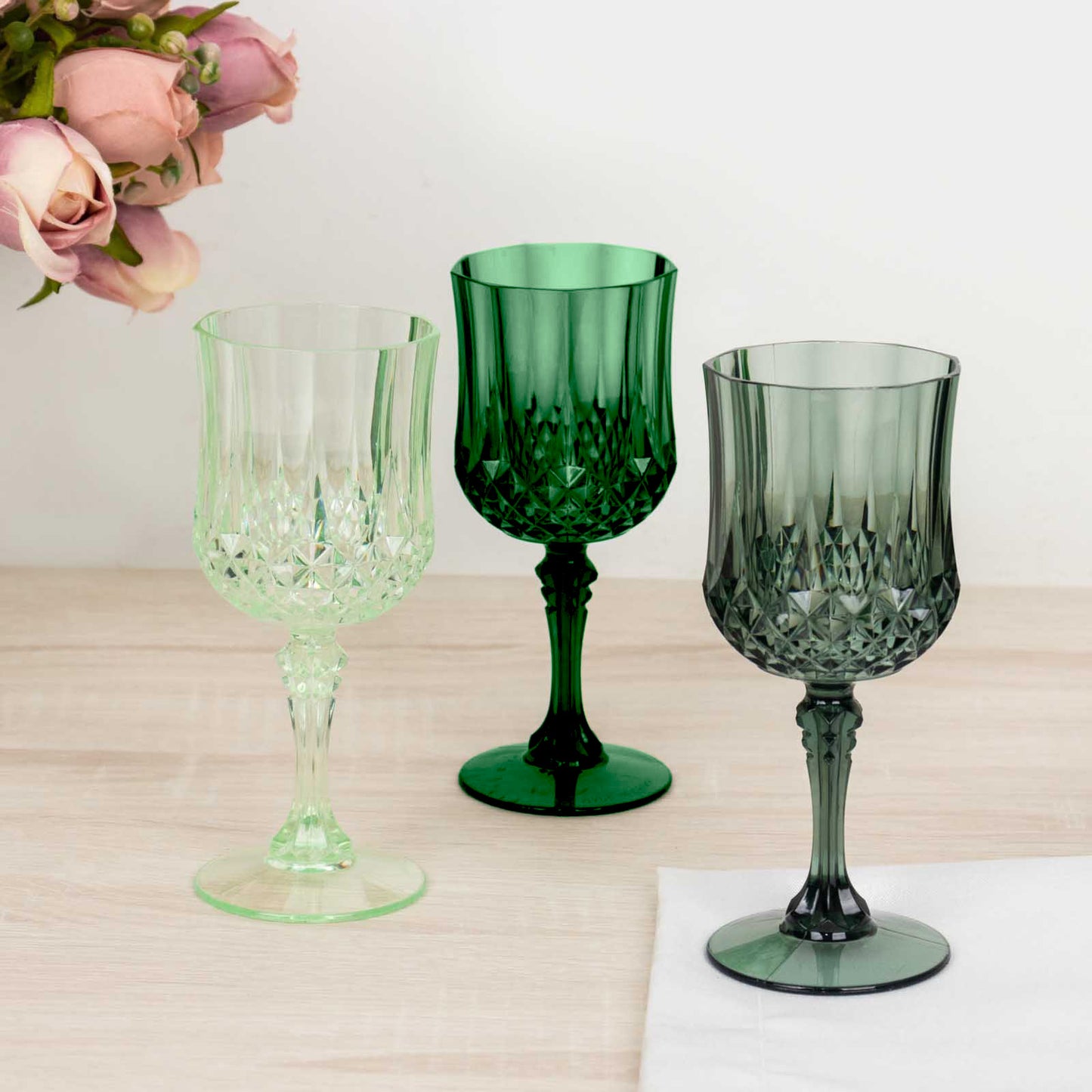 Assorted green crystal cut reusable plastic cocktail goblets.