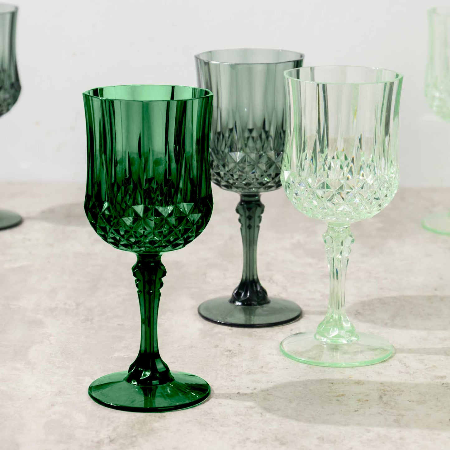 Assorted green crystal cut reusable plastic cocktail goblets.