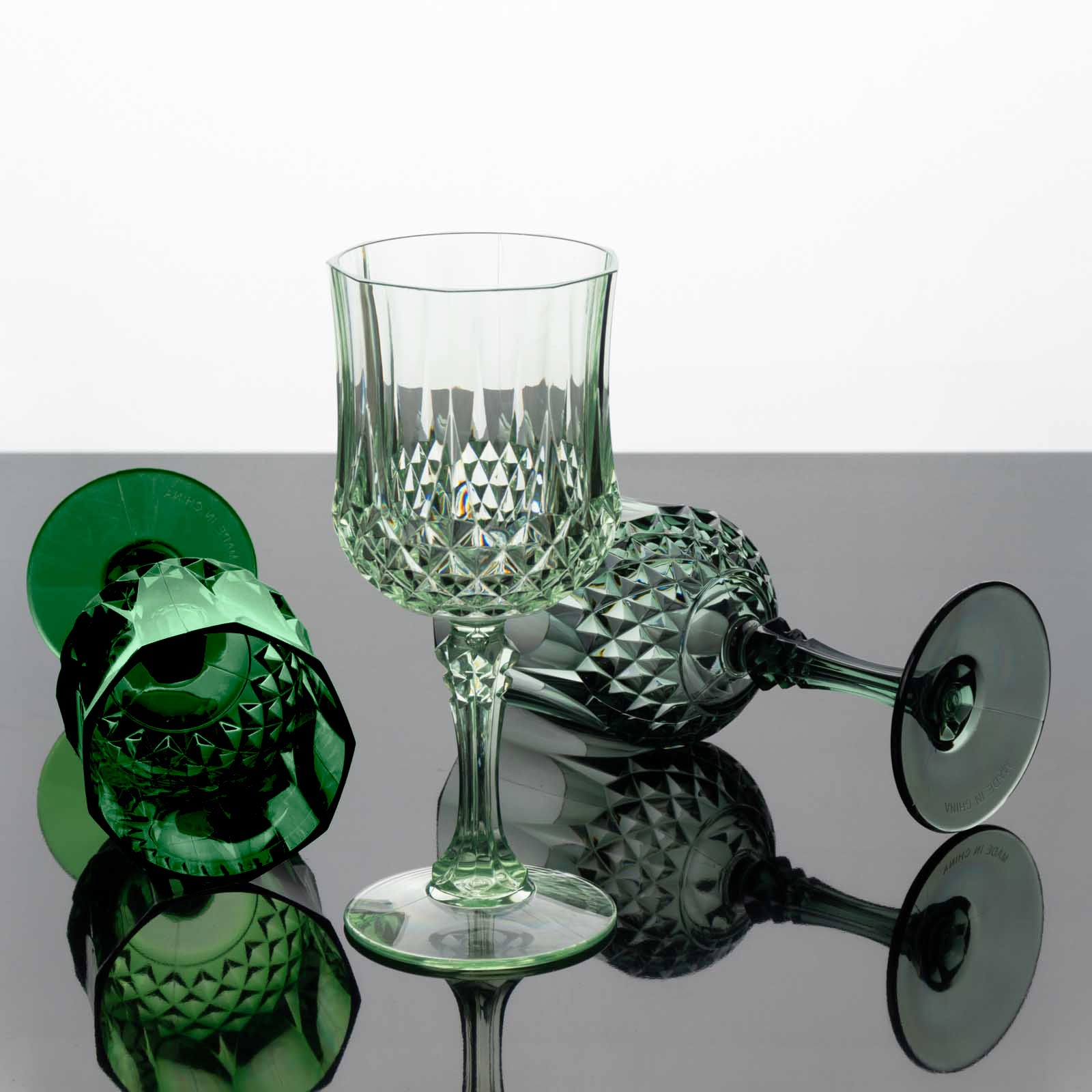 Assorted green crystal cut reusable plastic cocktail goblets.