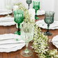 Assorted green crystal cut reusable plastic cocktail goblets on a table.