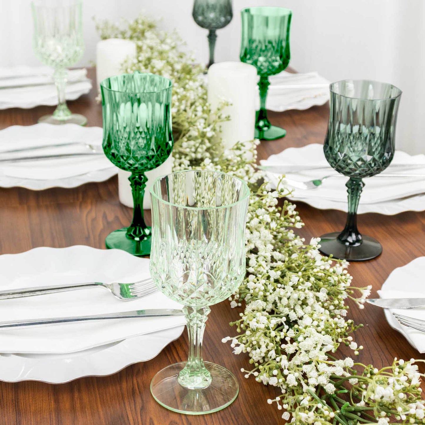 Assorted green crystal cut reusable plastic cocktail goblets on a table.
