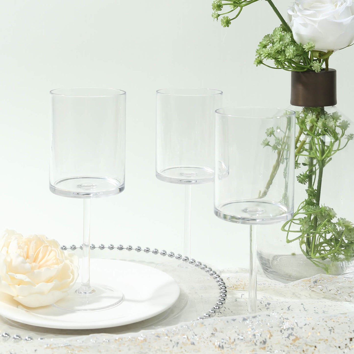 Clear plastic reusable cocktail glasses with long stems on a table setting.
