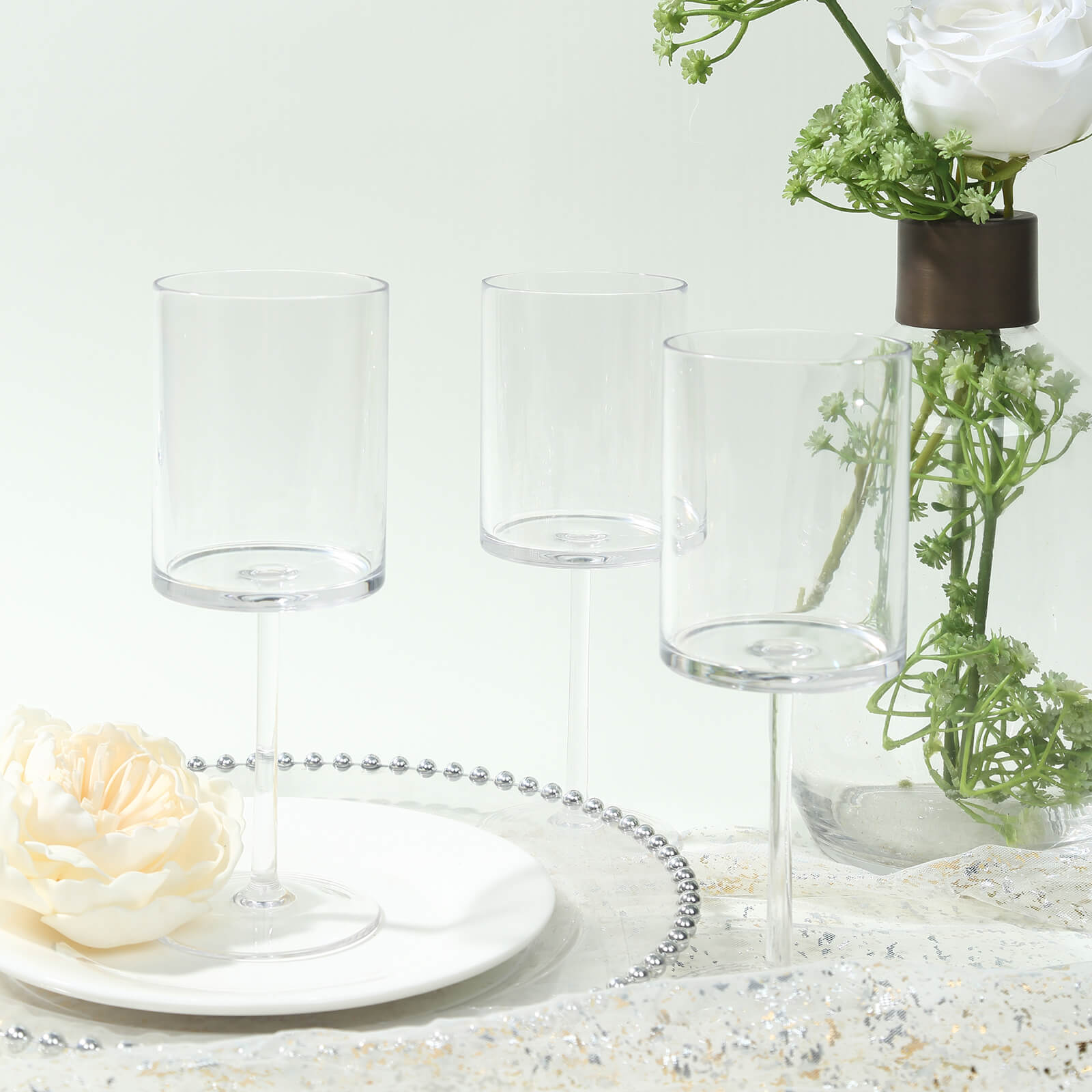 Clear plastic reusable cocktail glasses with long stems on a table setting.