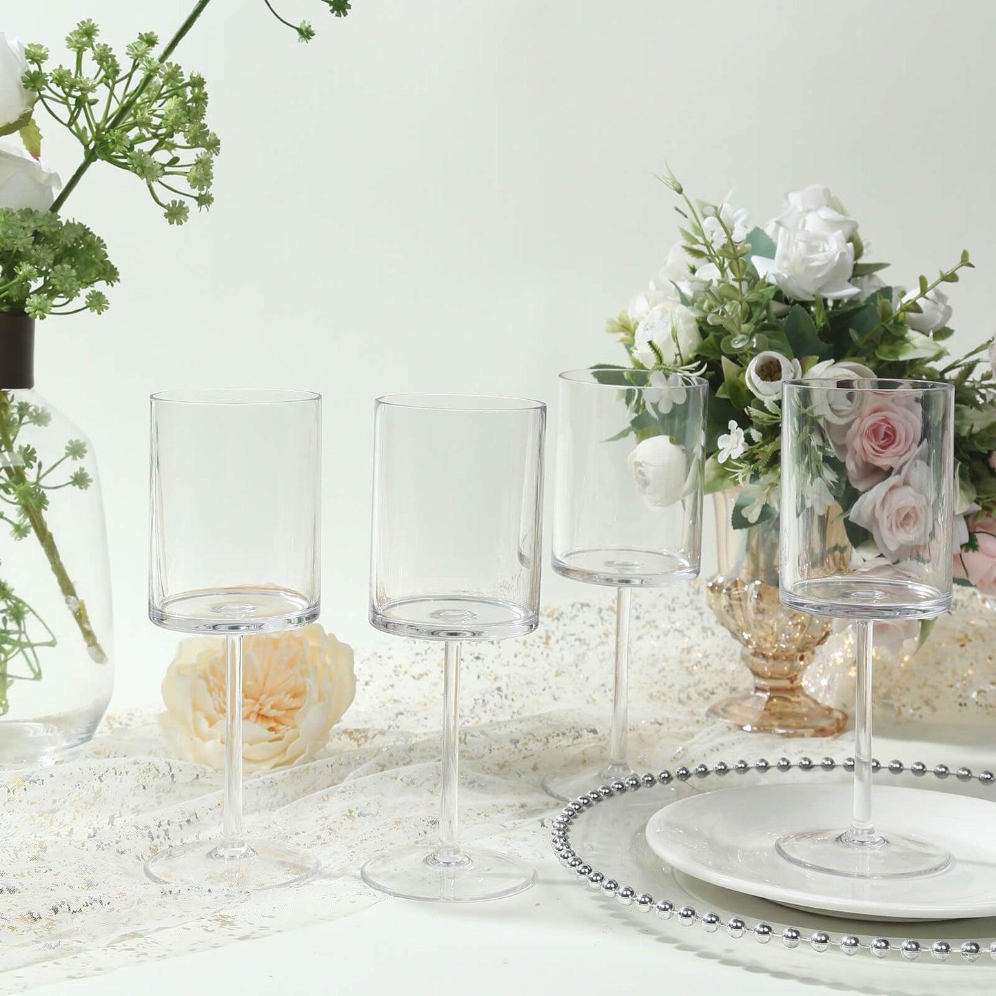 Clear reusable cocktail glasses with long stems in a floral setting.
