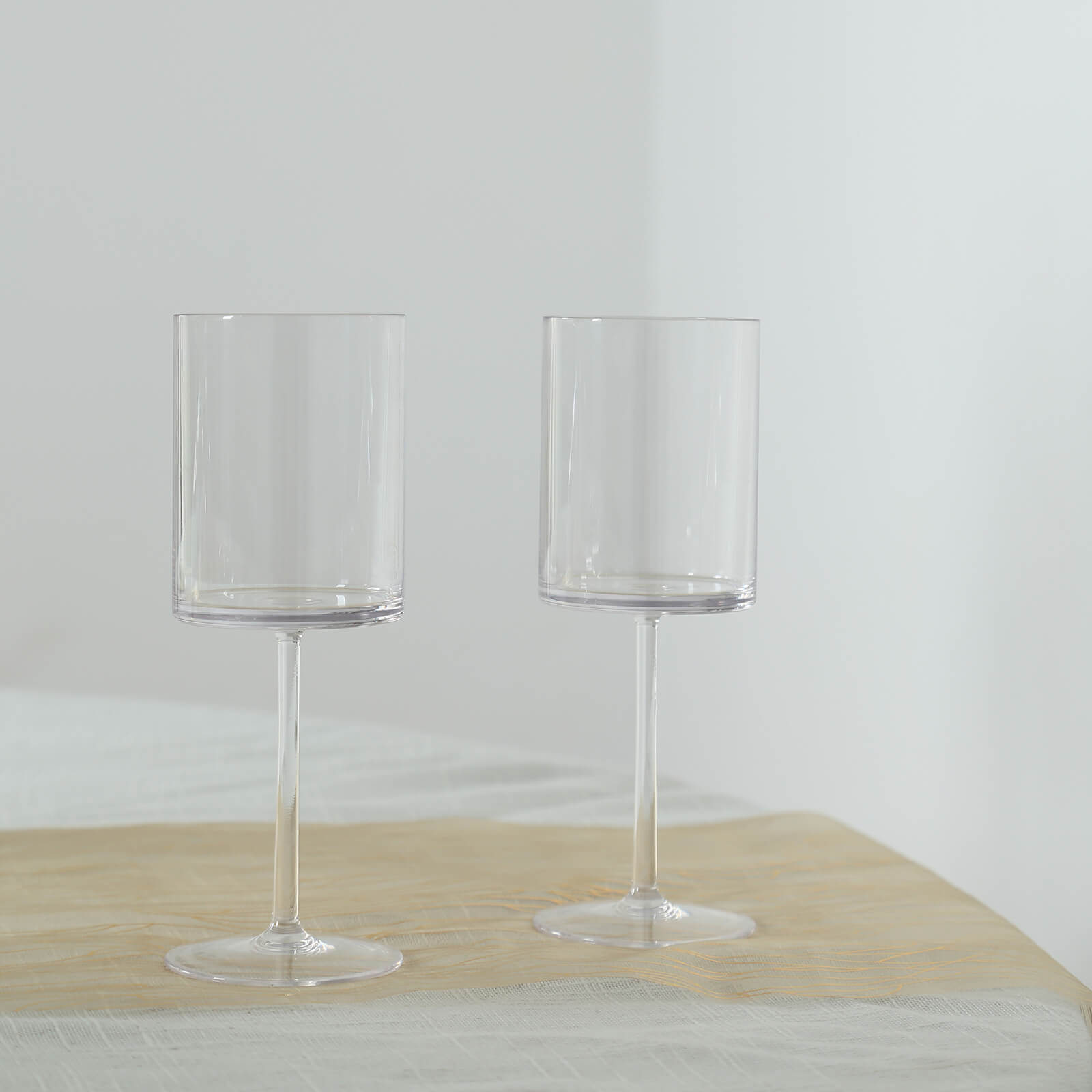 Clear plastic reusable cocktail glasses with long stems.