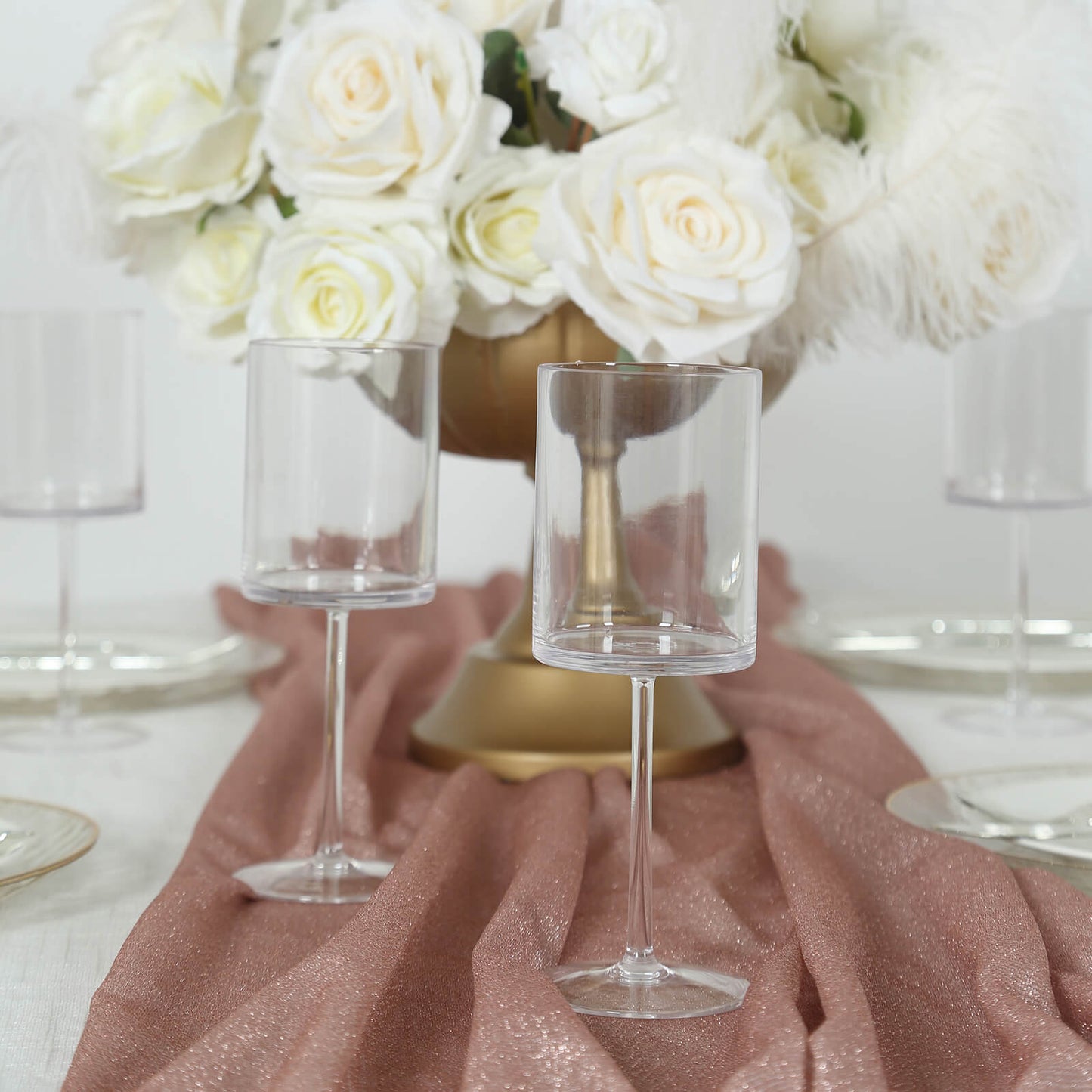 Clear plastic reusable cocktail glasses with long stem on a table setting.