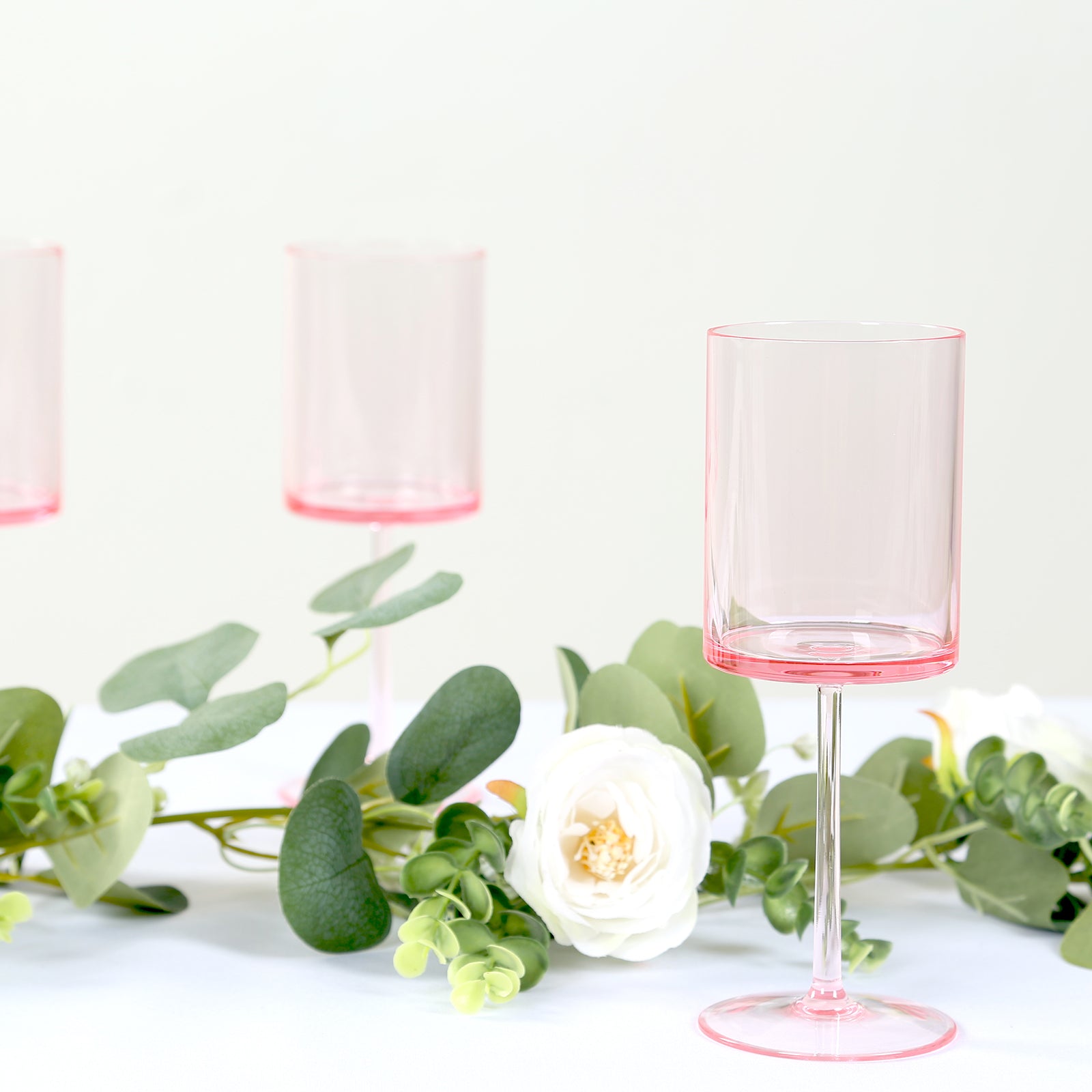 Transparent pink reusable cocktail glasses with long stems.