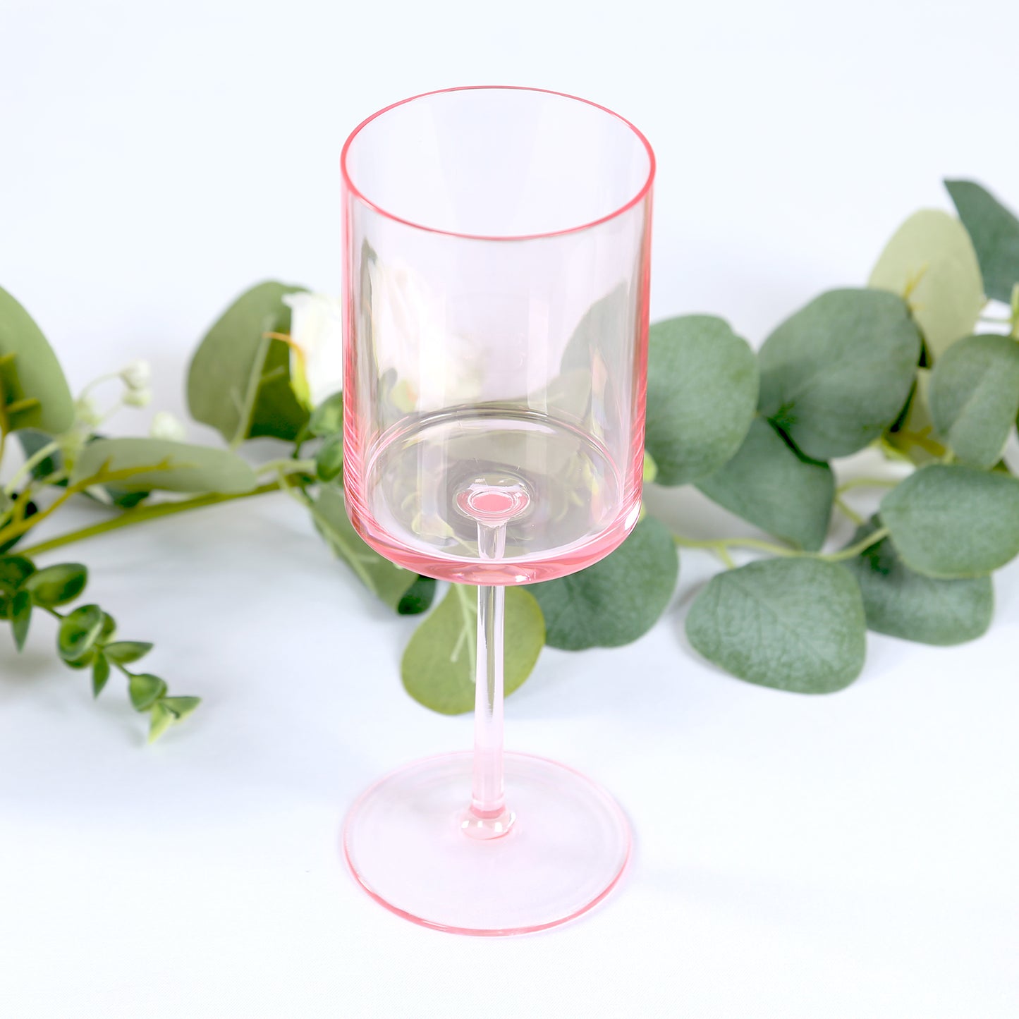 Transparent blush reusable cocktail glass with long stem.