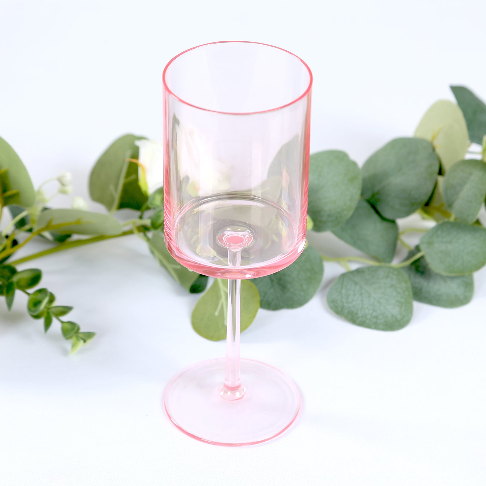 Transparent blush reusable cocktail glass with long stem.