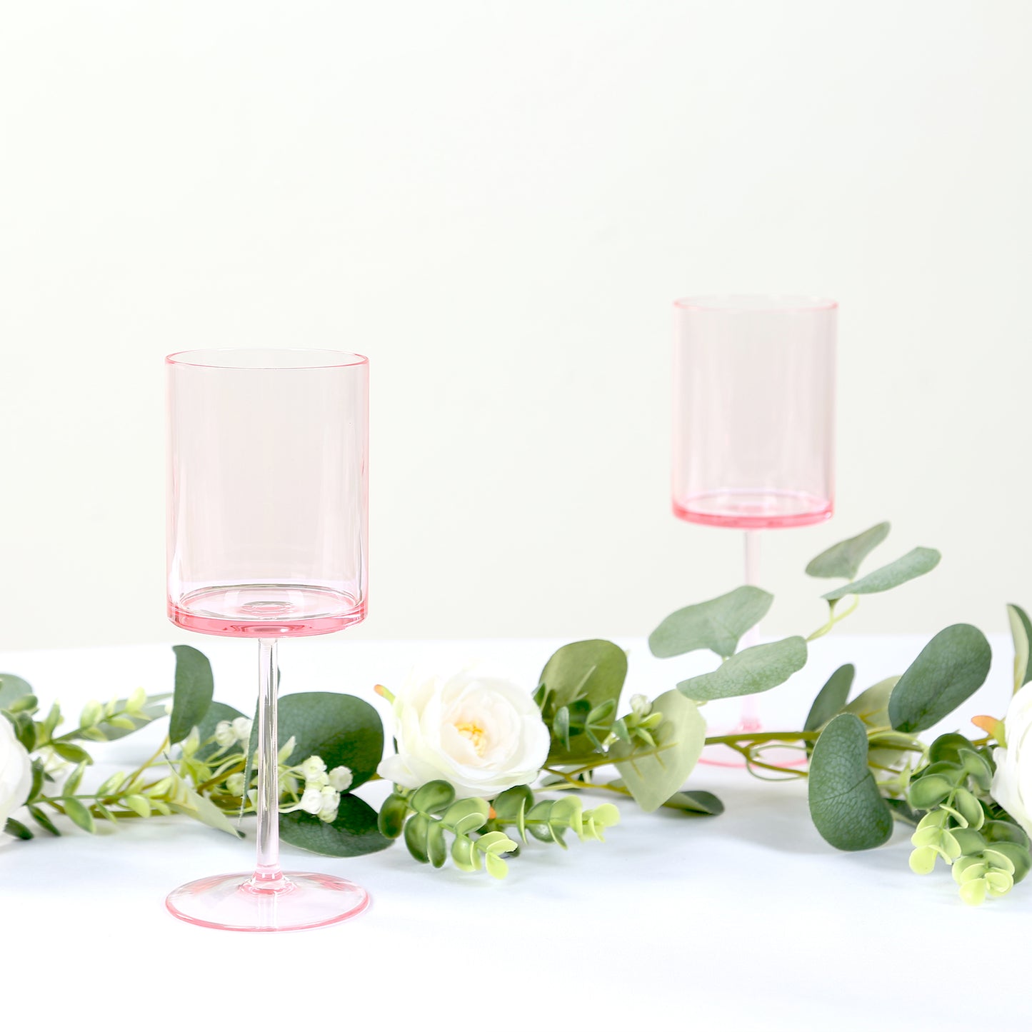 Transparent blush cocktail glasses with long stems.