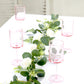 Transparent pink reusable cocktail glasses with long stems on a table.