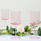 Transparent blush plastic reusable cocktail glasses with long stems.