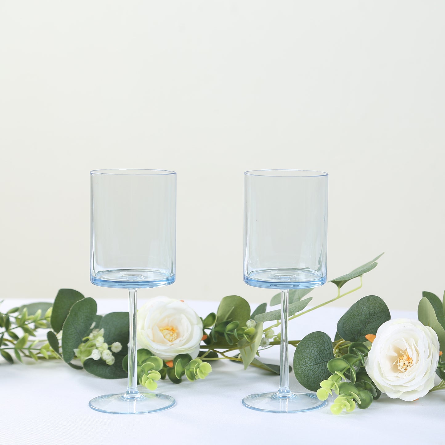 Transparent dusty blue reusable cocktail glasses with long stems.
