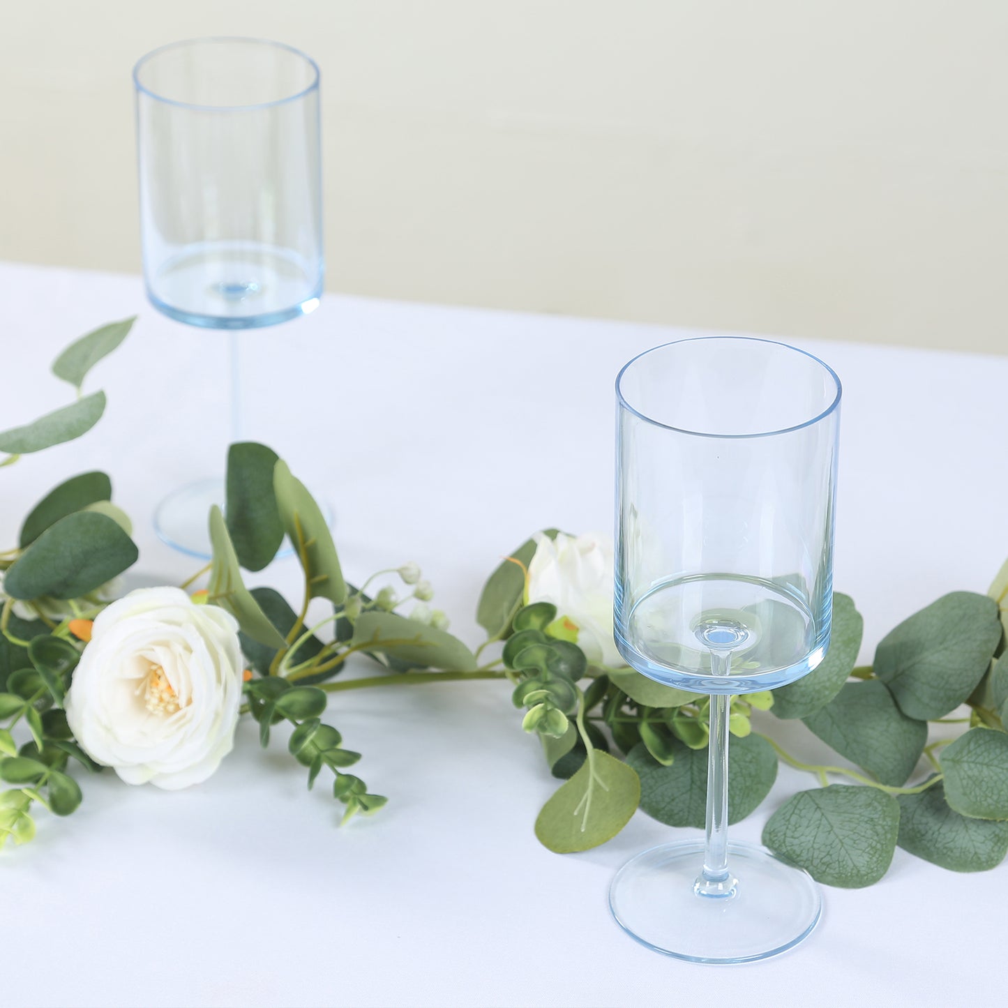 Transparent dusty blue reusable cocktail glasses with long stems.
