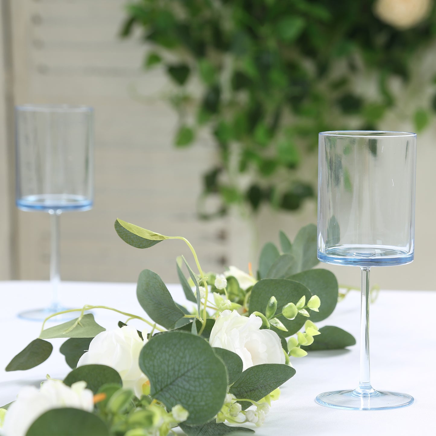 Transparent dusty blue reusable cocktail glasses with long stems.