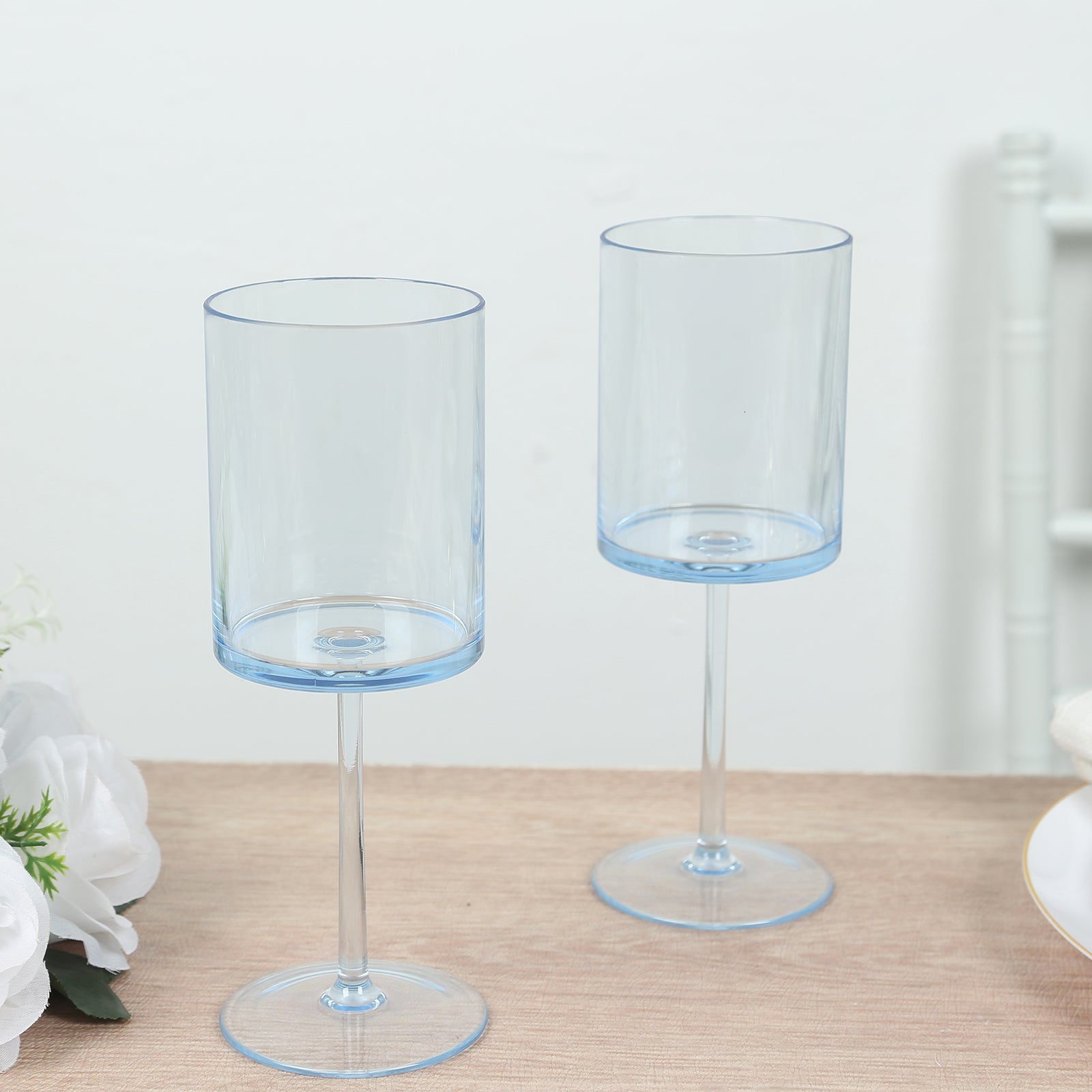 Transparent dusty blue cocktail glasses with long stems.