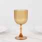 Amber gold ribbed reusable plastic wine goblet on a marble surface.