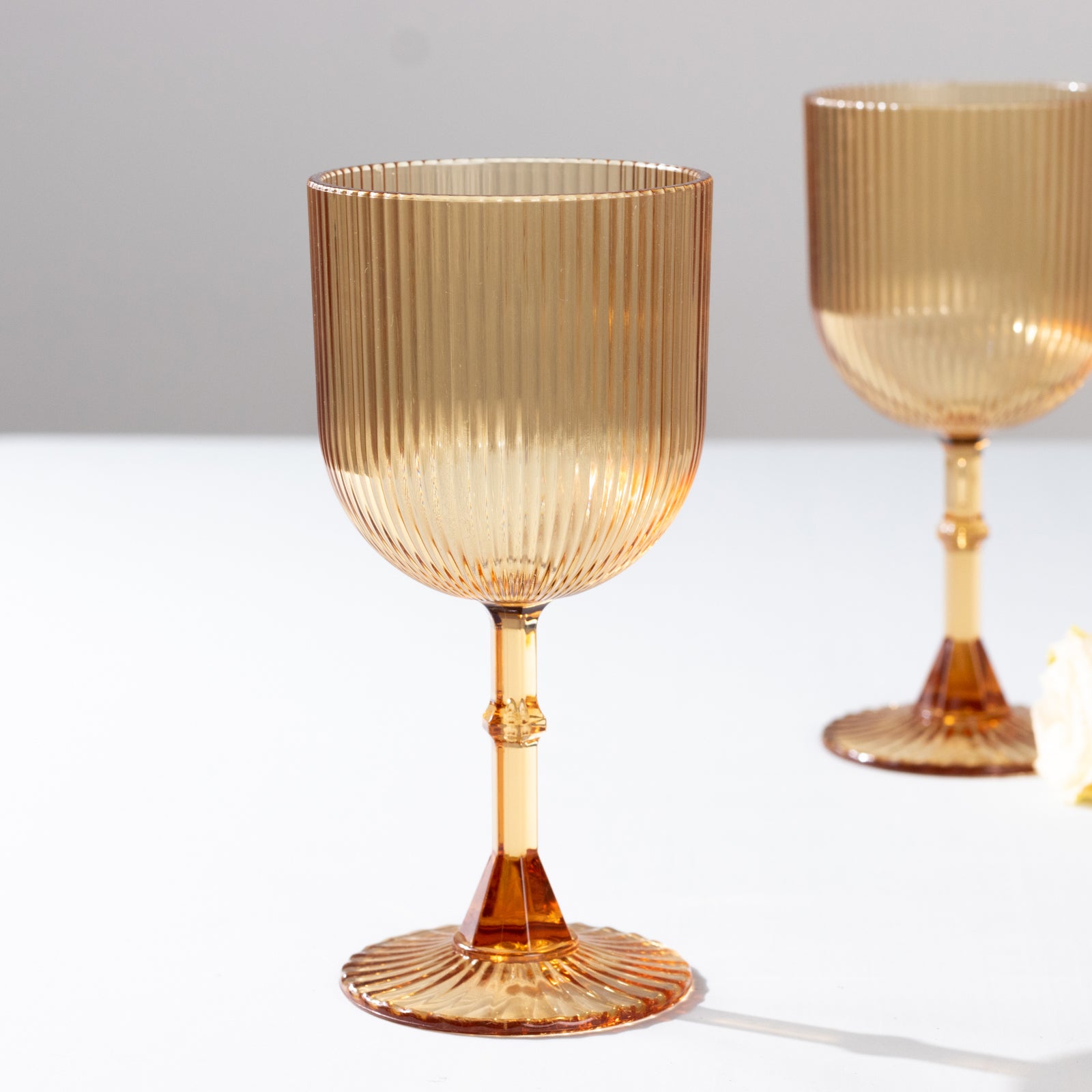 Amber gold ribbed reusable plastic wine goblets on a table.