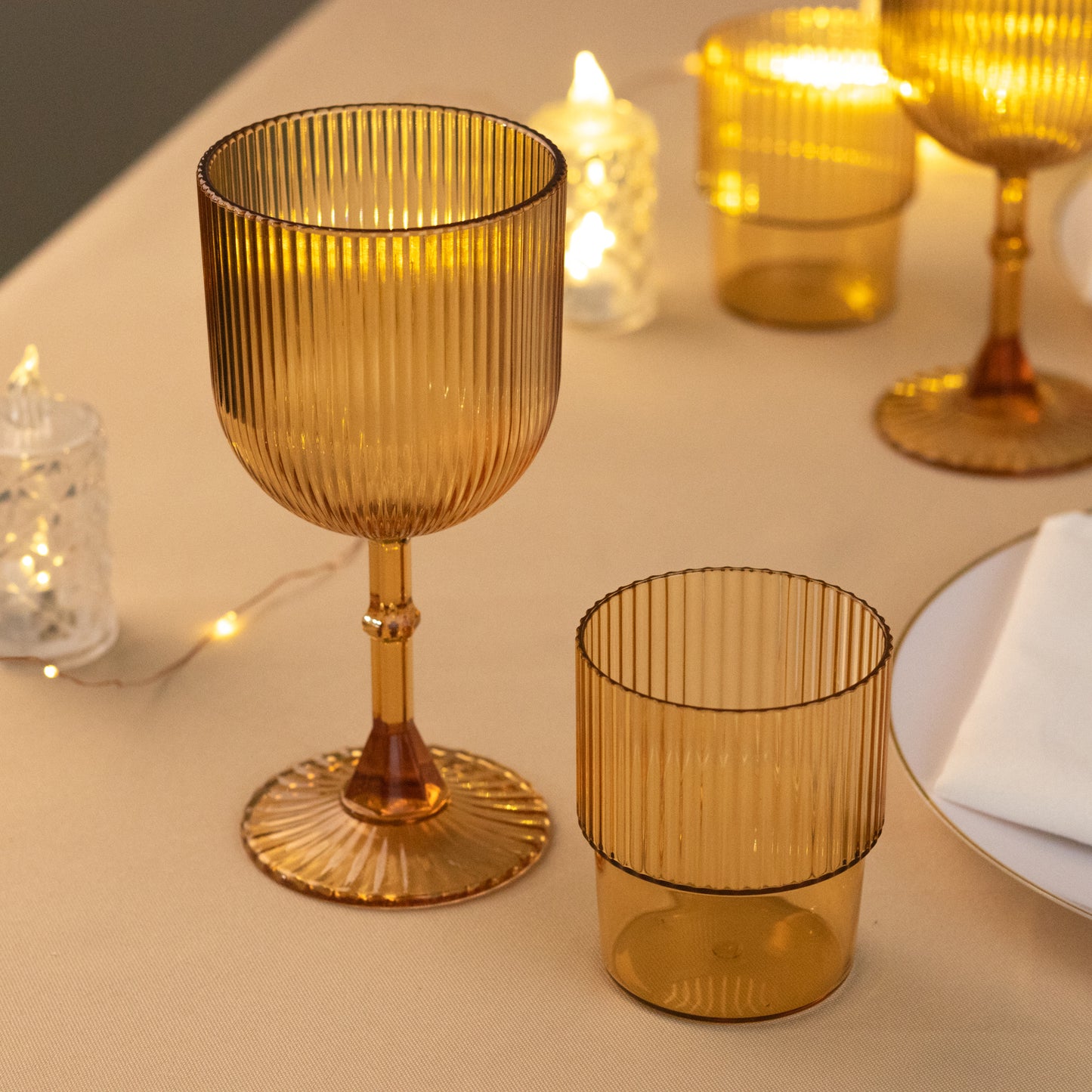 Amber gold ribbed reusable plastic wine goblets on a table.