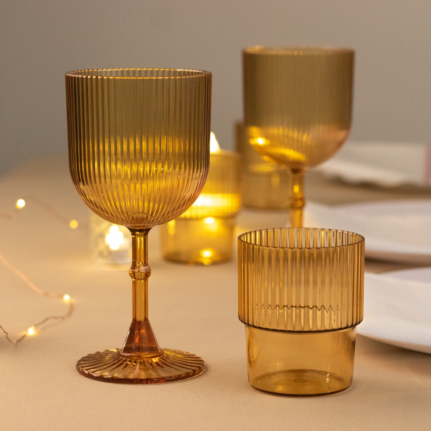 Amber gold ribbed reusable plastic wine goblets on a table.