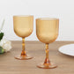 Amber gold ribbed reusable plastic wine goblets on a wooden table.