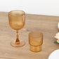 Amber gold ribbed reusable plastic wine goblets on a wooden table.