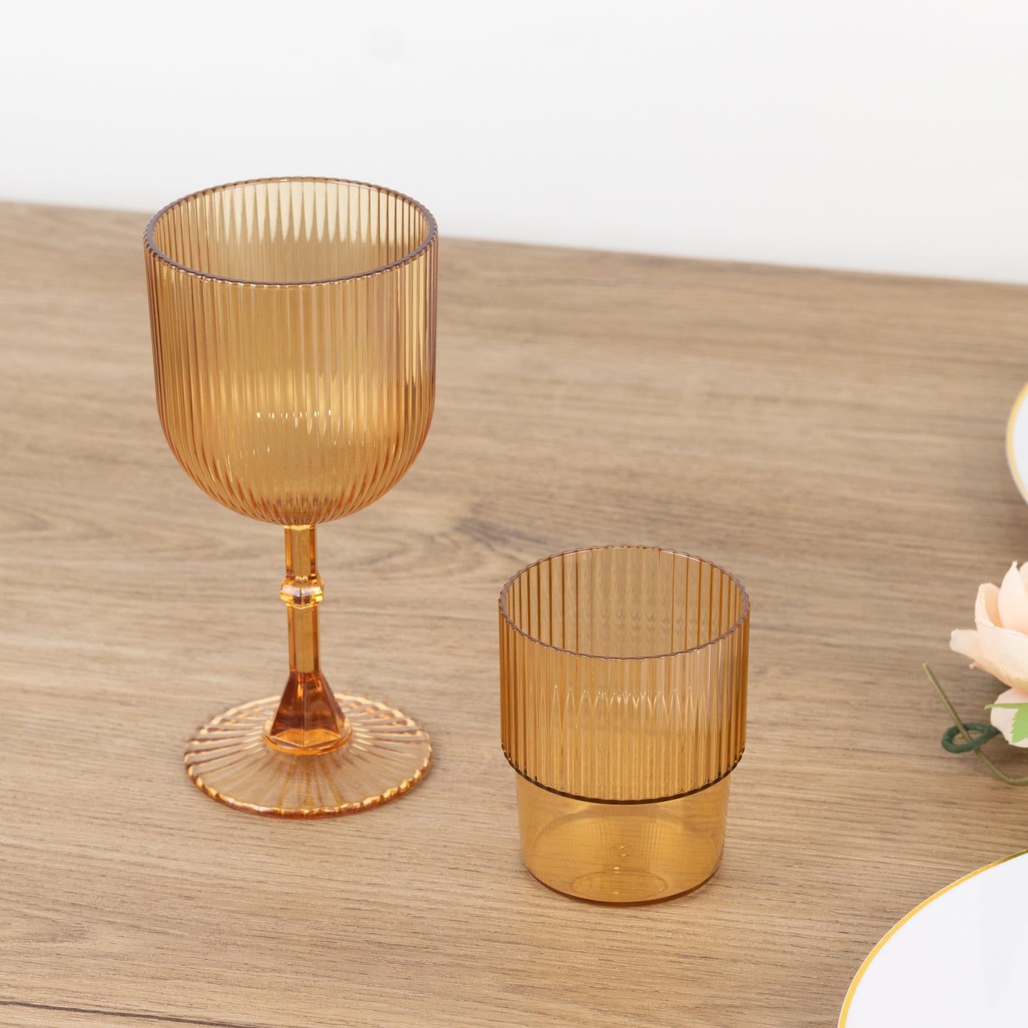 Amber gold ribbed reusable plastic wine goblets on a wooden table.
