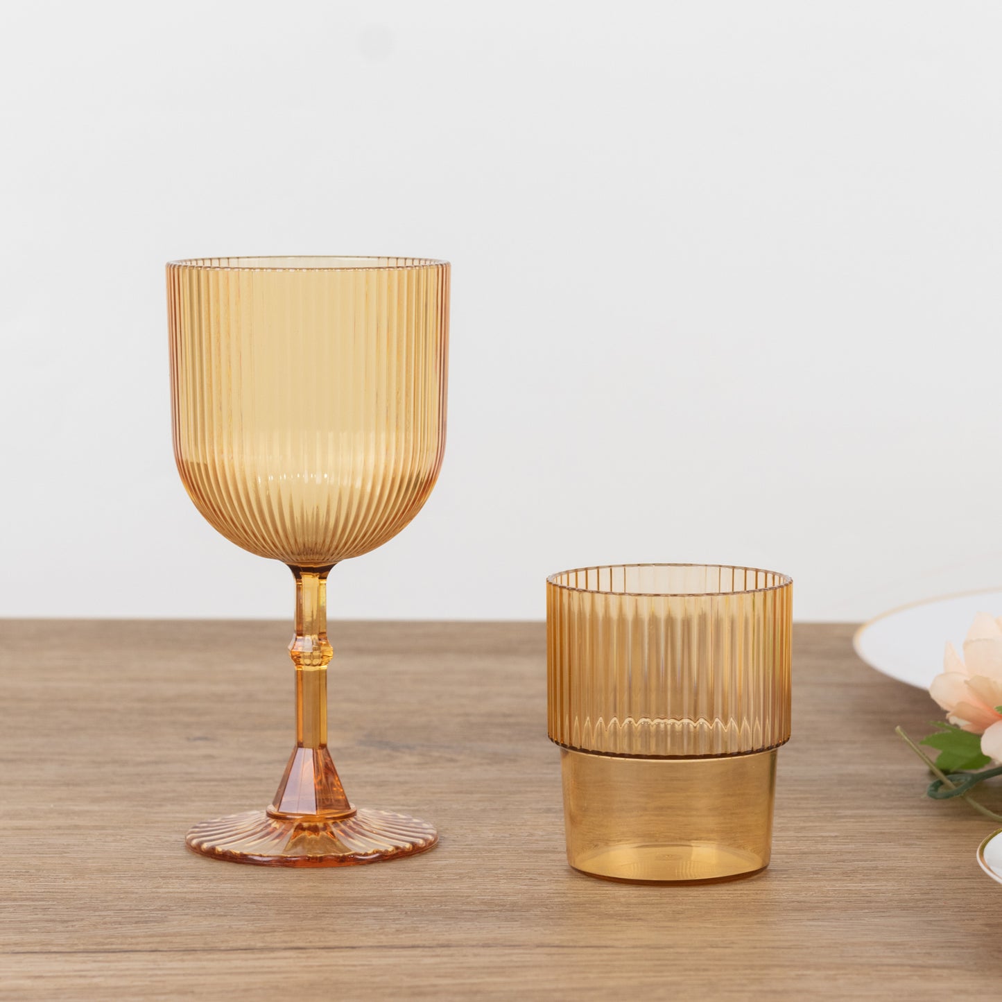 Amber gold ribbed reusable plastic wine goblet on a wooden surface.