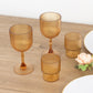 Amber gold ribbed reusable plastic wine goblets on a wooden table.