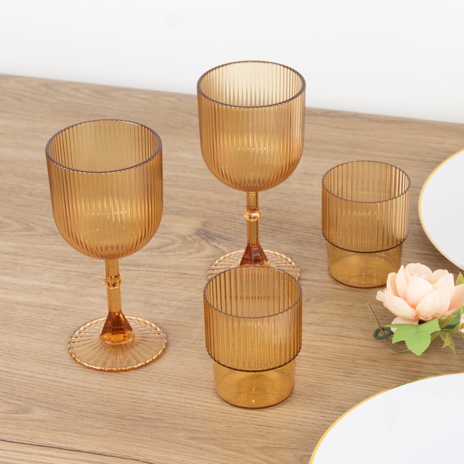 Amber gold ribbed reusable plastic wine goblets on a wooden table.
