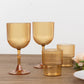 Amber gold ribbed reusable plastic wine goblets on a wooden table.