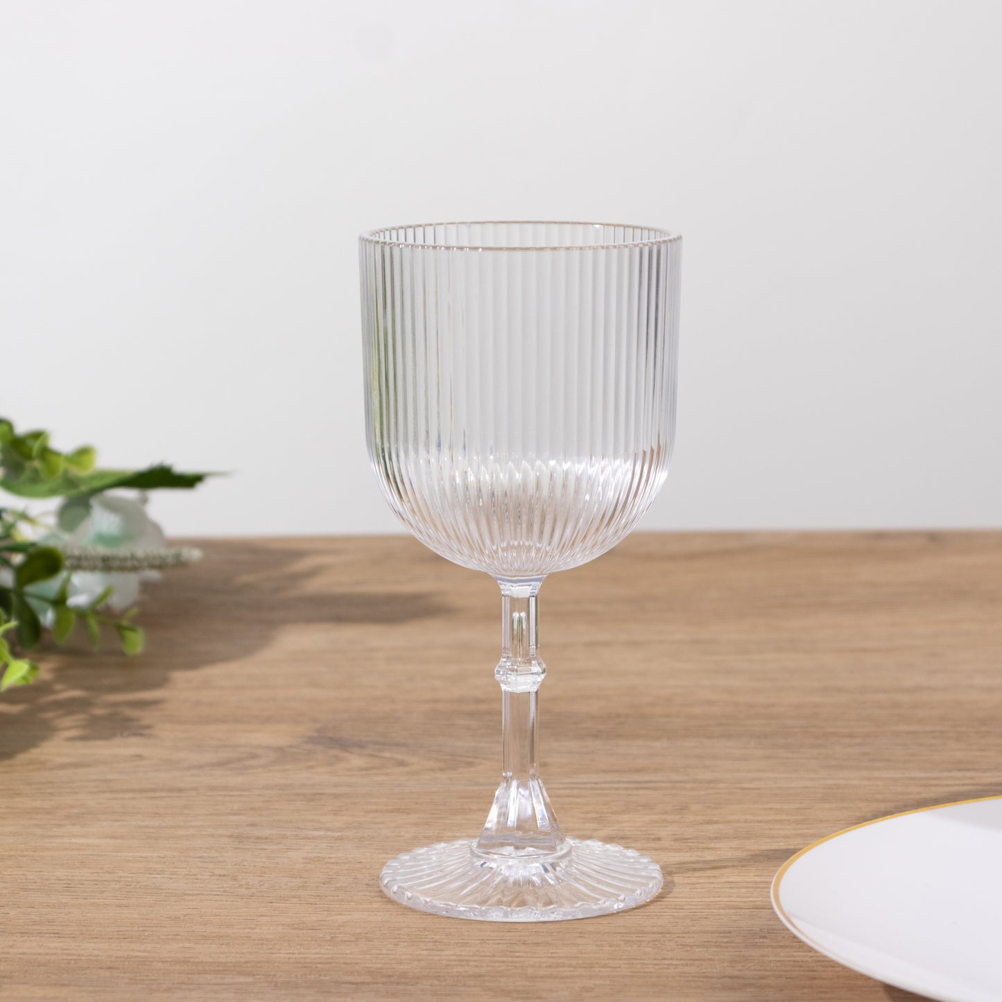 Clear ribbed plastic wine goblet on a wooden table.