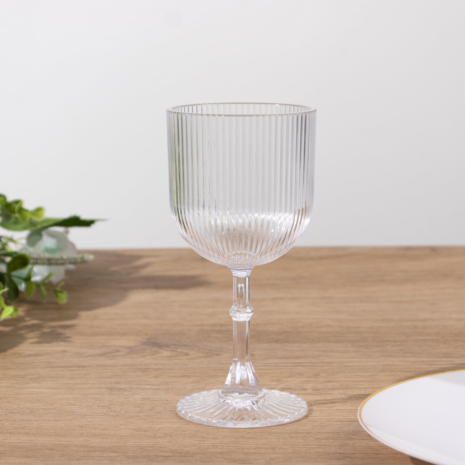 Clear ribbed plastic wine goblet on a wooden table.