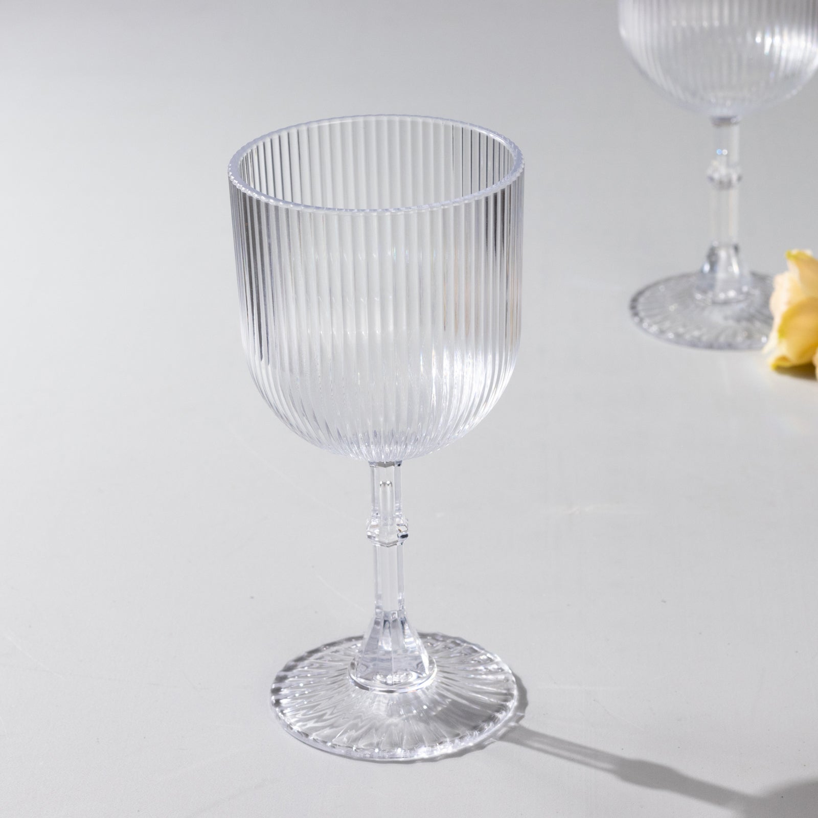 Clear ribbed reusable plastic wine goblet, shatterproof vintage design.