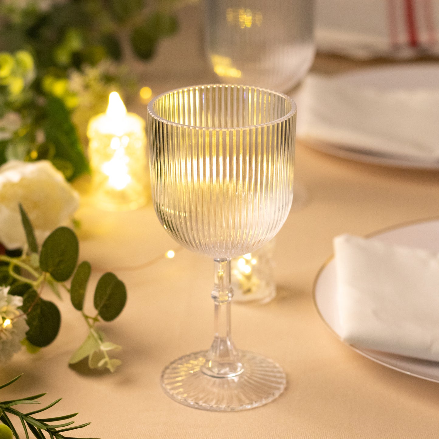 Clear ribbed reusable plastic wine goblet on a table setting.