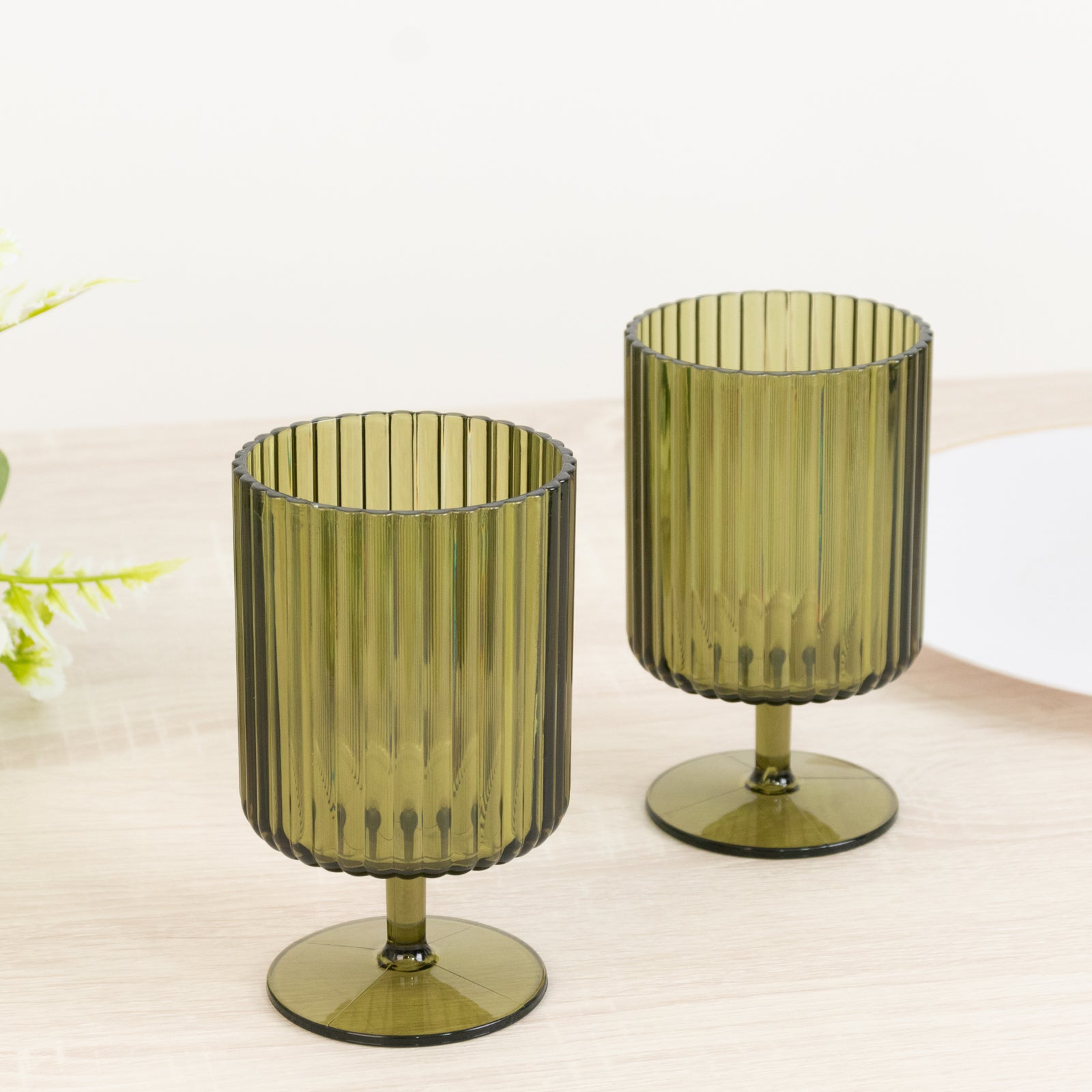 Dusty sage green ribbed plastic goblets on a table.